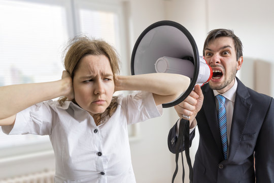 Mobbing At Work. Manager Is Shouting At His Secretary At Work With Megaphone.