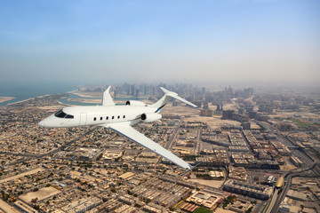 Business jet airplane flying over city.