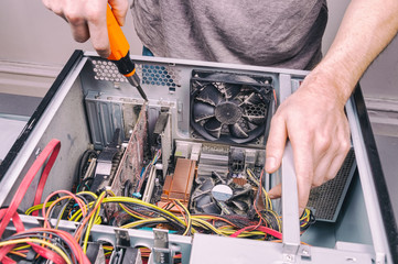 Man fixing an old desktop computer using a screwdriver