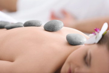 Young woman having stones massage in spa salon