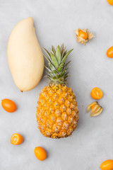Pineapple, mango, granadilla, kumquat, physalis on a gray background. Exotic fruits