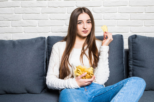 Young Attractive Woman Sitting On Sofa And Eating Chips At Home