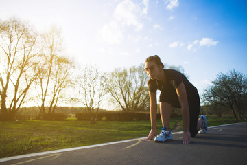 girl standing on asphalt treadmill and ready to run through a nature or park