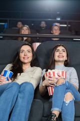 Two female friends watching a movie at the cinema together