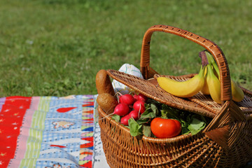 Fototapeta na wymiar Picnic basket with healthy food and blanket on green grass in park, nature. Lunch break outdoors . Relax, Leisure Lifestyle Concept
