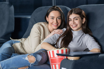 Fototapeta na wymiar Two female friends watching a movie at the cinema together