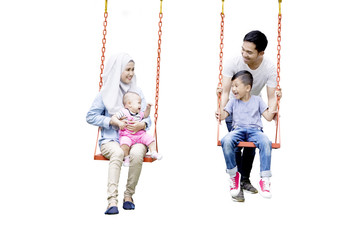Muslim family playing on swing