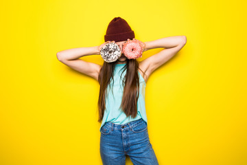 Slim hipster woman making glasses with two donutes yellow background