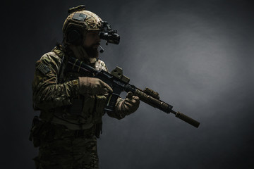 Bearded soldier in Combat Uniforms with weapon, plate carrier and combat helmet are on. Studio...