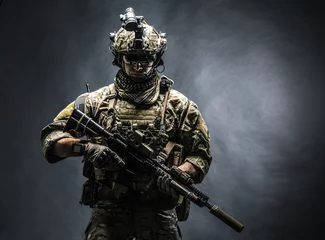 Poster Army soldier in Combat Uniforms with assault rifle, plate carrier and combat helmet are on, Shemagh Kufiya scarf on his neck. Studio shot, dark background © Getmilitaryphotos
