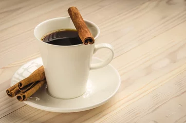 Fotobehang cup of coffee with cinnamon on a light tree/white cup of coffee with cinnamon sticks on a light tree © alexey351