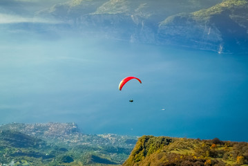 Paraglider flying over magnificent scenery of Garda lake, Italy