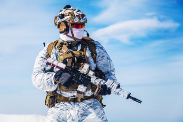 Army serviceman in winter camo somewhere in the Arctic. He wears chest rig and huge backpack,...