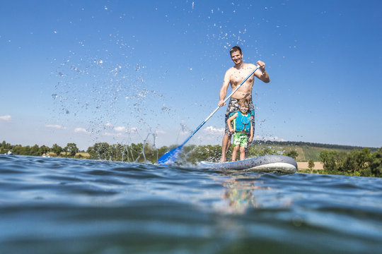 Vater und Sohn haben Spa&szlig; beim Standup-paddling auf dem See