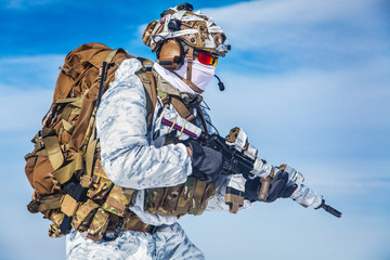 Army serviceman in winter camo somewhere in the Arctic. He wears chest rig and huge backpack,...