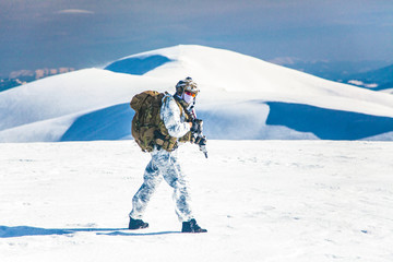 Army serviceman in winter camo somewhere in the Arctic. He wears chest rig and huge backpack,...