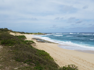 Waves break and crash towards the Hanakailio Beach with dramatic blue-pink cloudy skyline at dusk