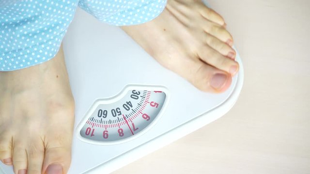 Female feet stepping on bathroom scales. Woman standing on weighing machine. Health care, weight loss concept. 4K ProRes HQ codec