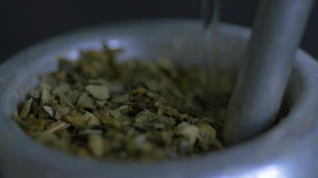 Close up macro of pouring hot water in mate fill with herb, a traditional beverage in Argentina
