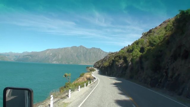 Road on ocean coast panorama view from car window in New Zealand. Scenic peaks and ridges. Beautiful background of amazing nature. Travel and tourism in the world of wildlife.
