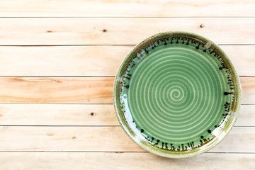 Top view of empty green ceramic plate on wooden background with copy space.