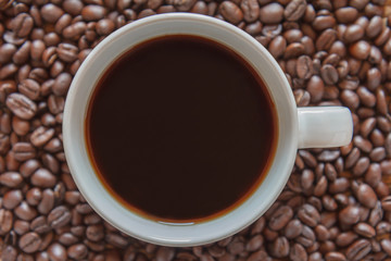 Coffee cup and coffee beans on old wood background