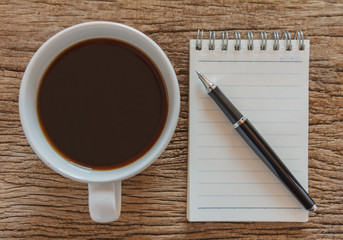 Blank notebook with pen and coffee on wooden table, business concept