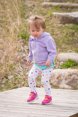 2 year old girl walking on a wooden bridge 