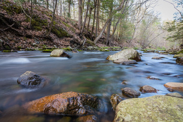 Naklejka na ściany i meble River flows gently along rocks in springtime