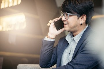 Handsome businessman in suit and eyeglasses speaking on the phone in office,Side view shot of a man's hands using smart phone in rear view of business man busy using cell phone at office.