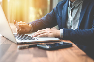 Handsome businessman in suit and eyeglasses Hands holding credit card and using laptop. Online shopping,Side view Hands holding credit card and using laptop. Online shopping