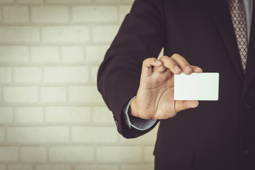 Man holding white business card on concrete wall background