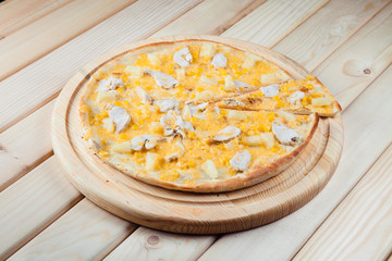 Pizza with pineapple on the wooden background