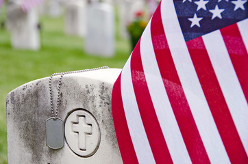 military dog tags and American flag on veteran's tombstone