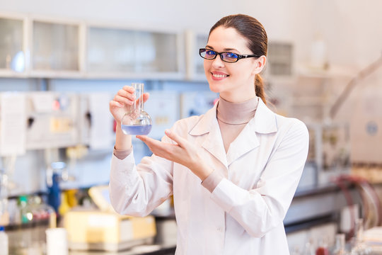 Woman scientist in laboratory with beaker posing
