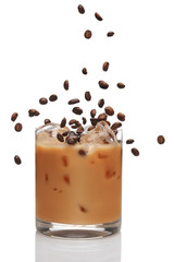Coffee beans falling into cocktail with Irish creme liqueur in a glass full of ice.