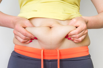 Overweight woman body with hands touching belly fat