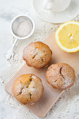 Lemon muffins with poppy seeds on a wooden stand on a light background. Selective focus.