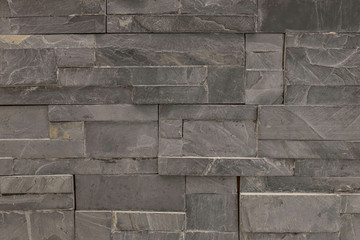 Closeup surface brick pattern at old black stone brick wall textured background
