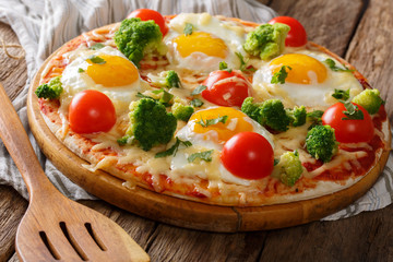 Delicious breakfast: pizza with eggs, broccoli, tomatoes and herbs close-up. horizontal