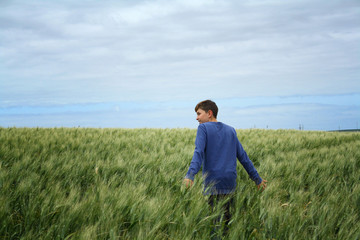 the boy in the blue sweater in the wheat field