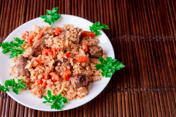 Pilaf on the white plate on a wooden table. Top view. Copy space.