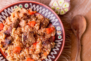 Pilaf on the brown plate on a wooden background. Top view. Copy space. Rustic style.