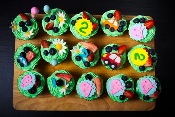 Set of homemade cupcakes with mastic decor for second birthday of child. Toned
