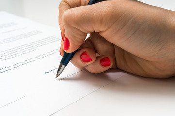 Female hand signing contract to conclude a deal