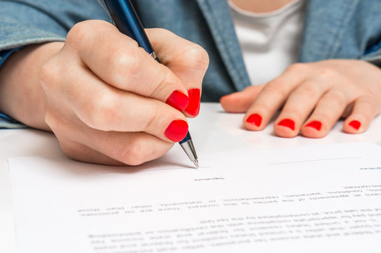 Woman with ballpoint pen signing contract document