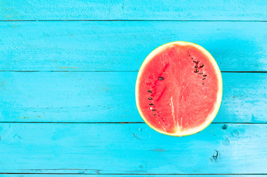 the summer watermelon is slice of half on a blue rustic wood background. copy space for designer