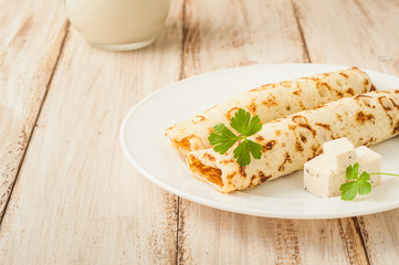 Food photography. Thin pancakes with filling and slices of cheese with herbs