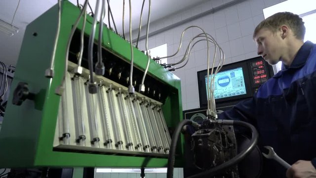 Fuel injection equipment repairing stand. Professional mechanic testing diesel injector in the Heavy machine workshop.