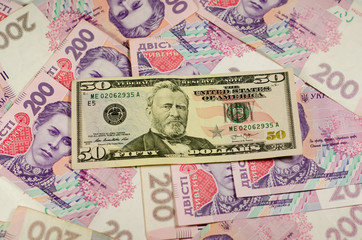 Fifty dollars banknote on the background of ukrainian hryvnas